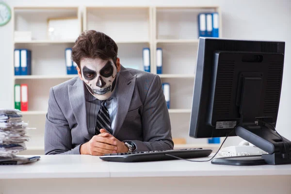 Businessmsn with scary face mask working in office