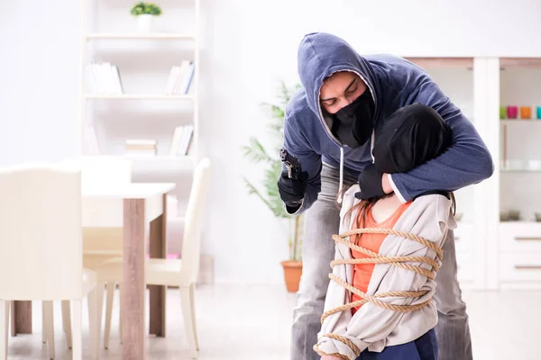 Armado homem assaltando jovem mulher em casa — Fotografia de Stock