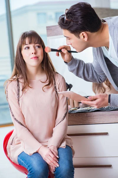 Muž dělá make-up pro roztomilé ženy v salonu krásy — Stock fotografie