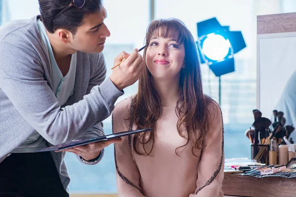 Hombre haciendo maquillaje para mujer linda en salón de belleza —  Fotos de Stock