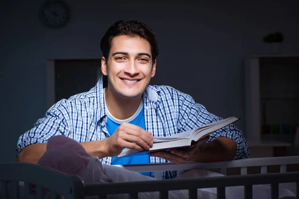 Молодой студент делает домашнее задание и ухаживает за новорожденным ребенком — стоковое фото