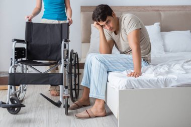 Üzgün karısıyla birlikte tekerlekli sandalyedeki umutsuz adam.