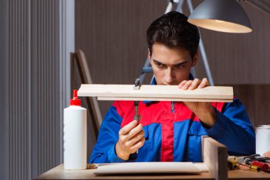 Genç adam ahşap parçaları DIY konseptinde yapıştırıyor.