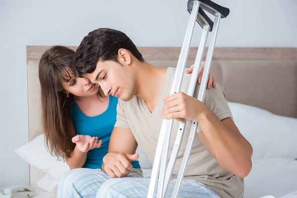 Junge Frau stützt Ehemann nach Verletzung auf Krücken — Stockfoto