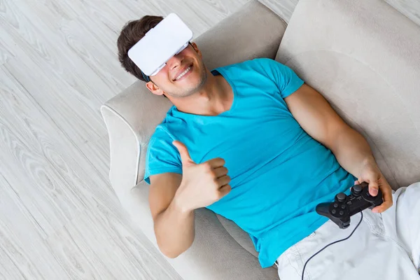 Hombre joven con gafas VR relajándose en sofá —  Fotos de Stock