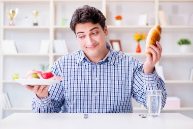 Diyet dolandırıcılığında sağlıklı yemek ve ekmek arasında ikilem yaşayan bir adam.