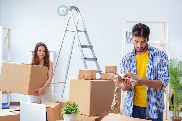 Молодая семья распаковывает в новом доме коробки