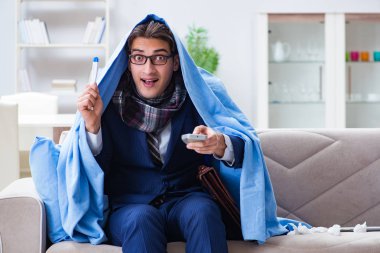Çalışan işadamı grip olmuşken televizyon izliyor.