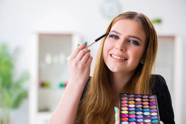Mujer joven aplicando maquillaje preparándose para la fiesta —  Fotos de Stock