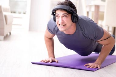 Adam evde spor yapıyor ve müzik dinliyor.