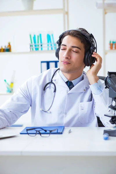 Happy excited doctor listening to music during lunch break in hospital