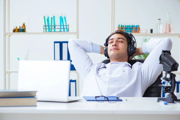 Happy excited doctor listening to music during lunch break in hospital