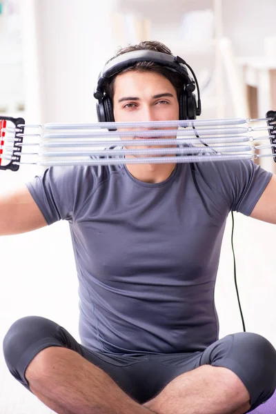 Homme faisant du sport avec un groupe de résistance et écoutant de la musique — Photo