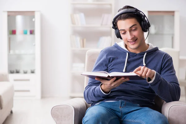 Joven leyendo libro y escuchando audio libro — Foto de Stock