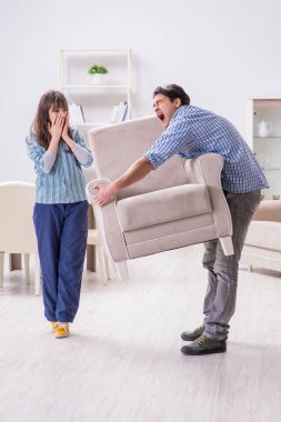 Oturma odasında koltuğu hareket ettiren bir adam.