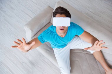 VR gözlüklü genç adam kanepede dinleniyor.