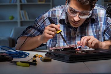 Genç tamirci ana yaban domuzunun elektrik parçalarını lehimliyor.