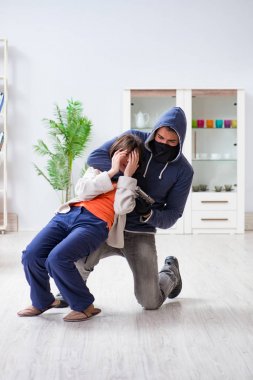 Silahlı bir adam evde genç bir kadına saldırıyor.