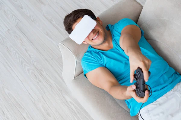 Hombre joven con gafas VR relajándose en sofá —  Fotos de Stock