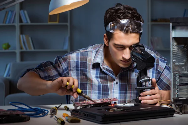 Ремонтник пытается починить ноутбук с помощью микроскопа — стоковое фото