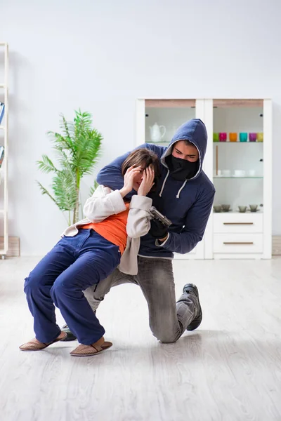 Ozbrojený muž napadá mladou ženu doma — Stock fotografie