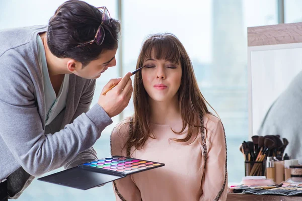 Muž dělá make-up pro roztomilé ženy v salonu krásy — Stock fotografie