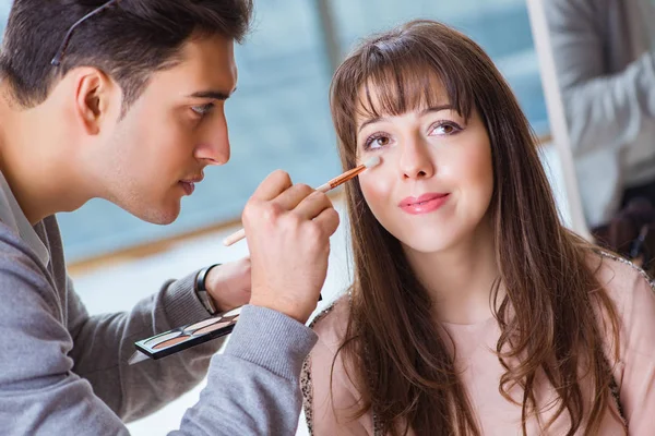 Мужчина делает макияж для симпатичной женщины в салоне красоты — стоковое фото