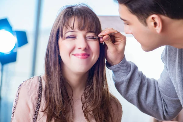 Güzellik salonunda güzel bir kadın için makyaj yapan adam.