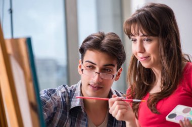 Stüdyoda resim sınıfında sanatçı koçluğu yapan bir öğrenci.