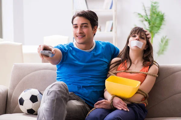 Hombre atando a su esposa para ver deportes de fútbol — Foto de Stock