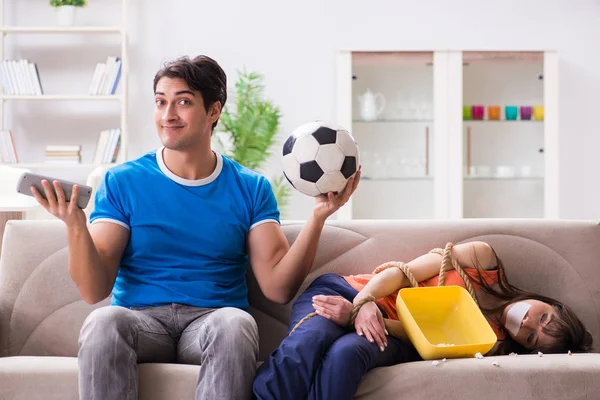 Мужчина связывает свою жену, чтобы смотреть спортивный футбол — стоковое фото
