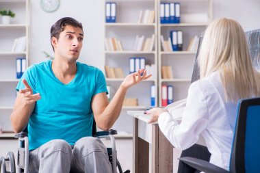 Tekerlekli sandalyedeki engelli adam kadın doktoru ziyaret ediyor.