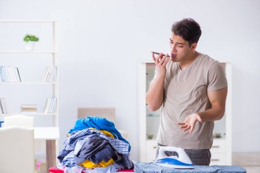Genç adam evde çamaşır ütülüyor.
