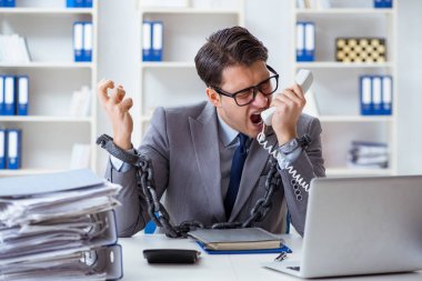 Ofis masasına zincirlenmiş meşgul bir çalışan.