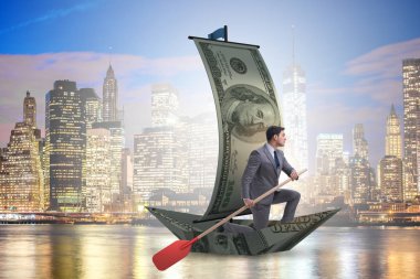 Ticari mali konseptte dolar teknesinde kürek çeken bir işadamı