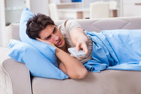 Uomo guardando la tv dal letto tenendo unità di controllo remoto — Foto Stock