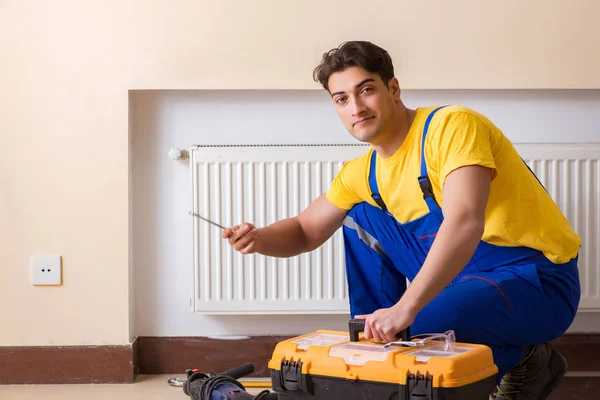 Young repairman contractor repairing heating panel