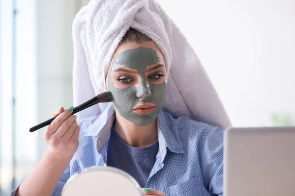 Frau trägt Tonmaske zu Hause mit Pinsel auf — Stockfoto