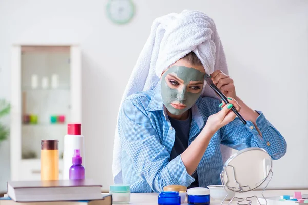 Frau trägt Tonmaske zu Hause mit Pinsel auf — Stockfoto