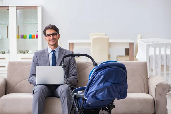 Businessman looking after newborn baby at home and teleworking — Stock Photo, Image