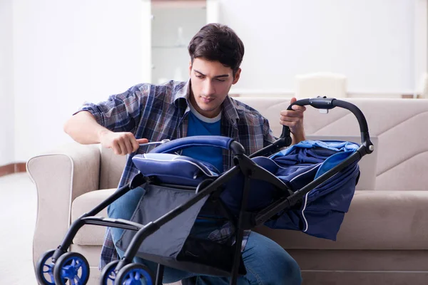 Jovem pai montando carrinho de bebê em casa — Fotografia de Stock