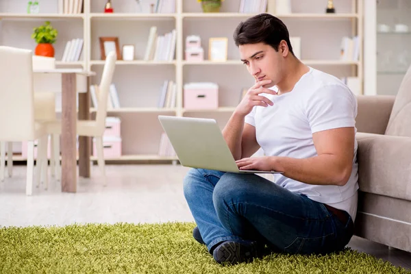 Uomo che lavora sul computer portatile a casa sul pavimento del tappeto — Foto Stock