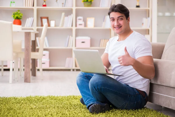 Uomo che lavora sul computer portatile a casa sul pavimento del tappeto — Foto Stock