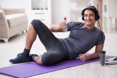Adam evde spor yapıyor ve müzik dinliyor.