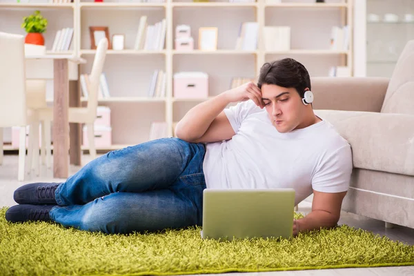 Homem trabalhando no laptop em casa no chão do tapete — Fotografia de Stock