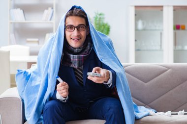 Çalışan işadamı grip olmuşken televizyon izliyor.