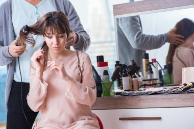 Erkek stilisti bir kadınla güzellik salonunda çalışıyor.