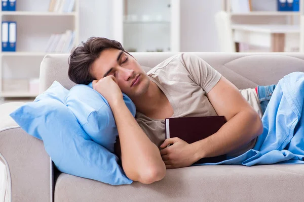 Jovem estudante se preparando para exames universitários na cama com livro — Fotografia de Stock