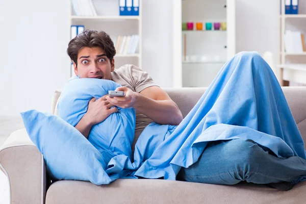 Человек смотрит телевизор из кровати держа пульт дистанционного управления — стоковое фото