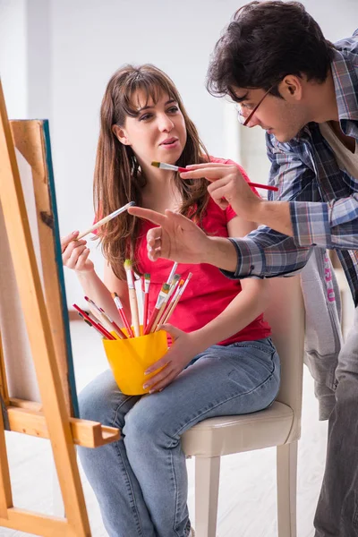 Artist coaching student in painting class in studio